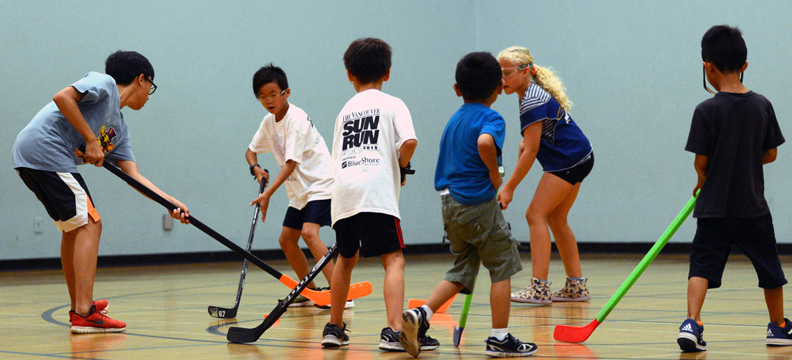 a group of kids playing hockey with plastic sticks in a gymnasium
