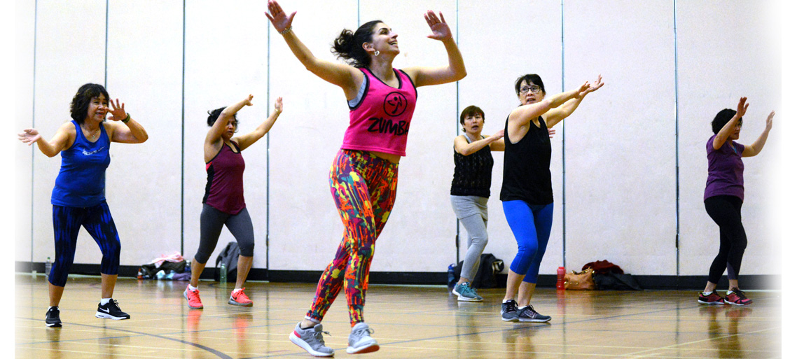 Zumba class at CNH. Participants are following the instructor and moving their arms in the air from side to side.