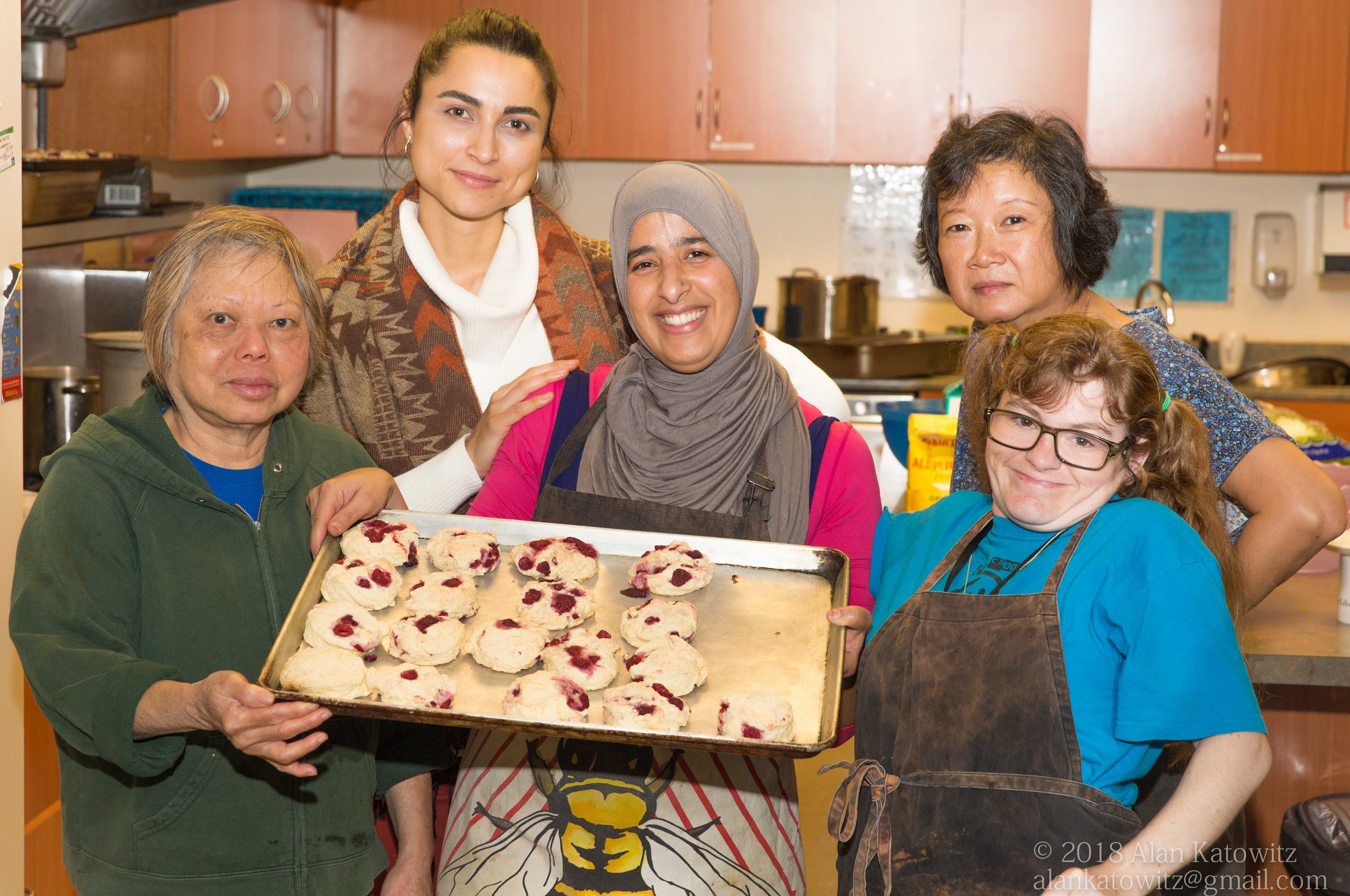 Staff and volunteers holding a baking pan of raspberry scones.