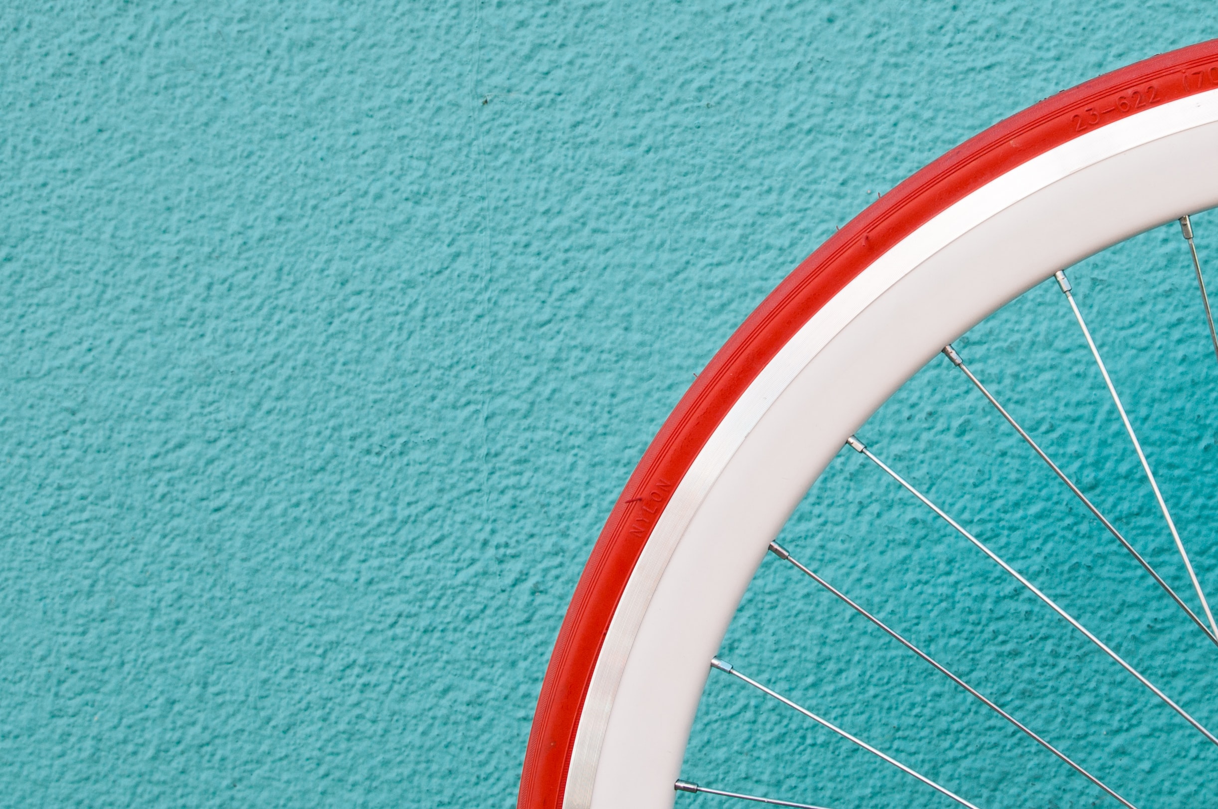 A red bike tire is against a bright blue wall