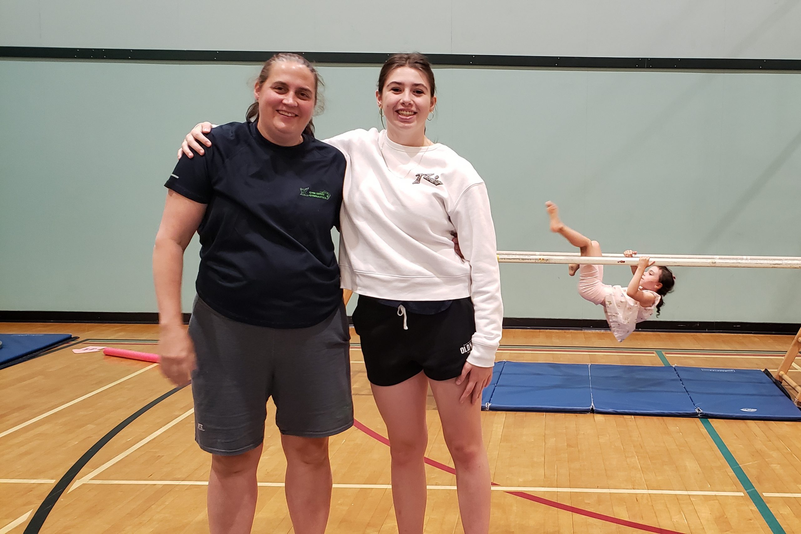 Lucinda Donaldson and Kyla Hanlon stand inside a gym. Kyla's arm is over Lucinda's shoulder.