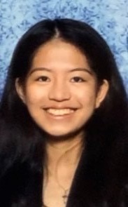 A close-up of a person wuth long dark hair smiling towards the camera