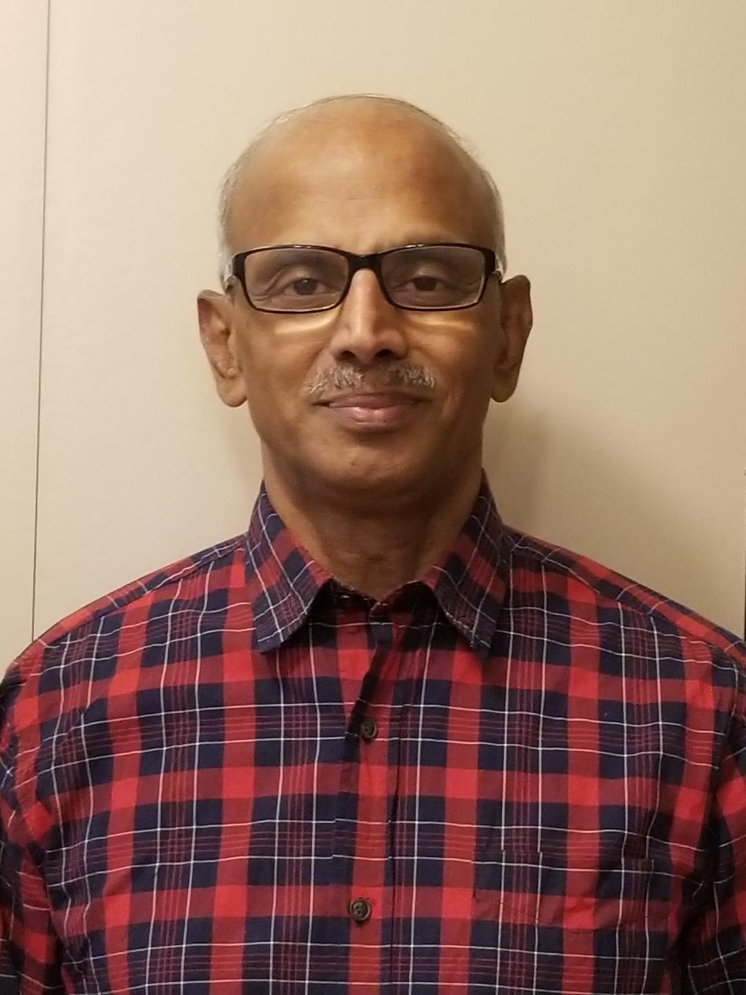 A close-up of a man wearing glasses and a red checkered shirt