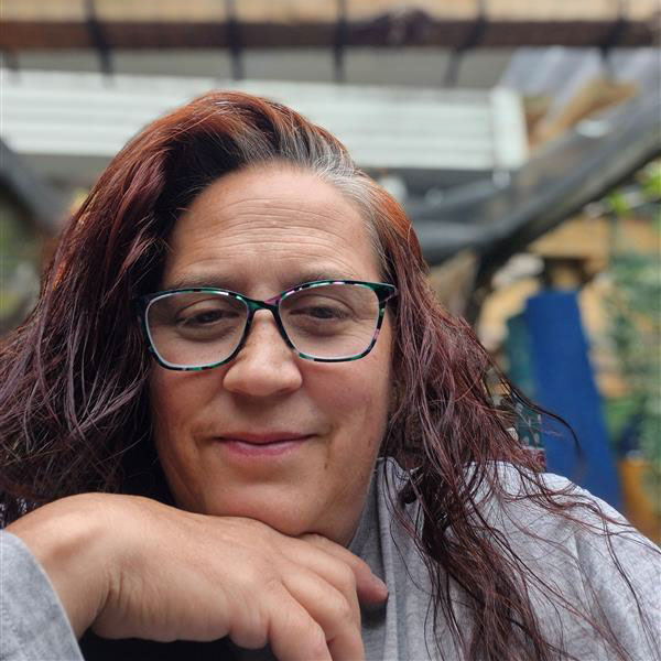 A close-up of a woman with long red hair wearing glasses