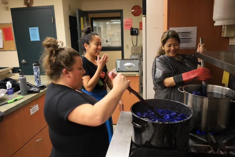 Three people stand around a commercial stove inside the kitchen at CNH