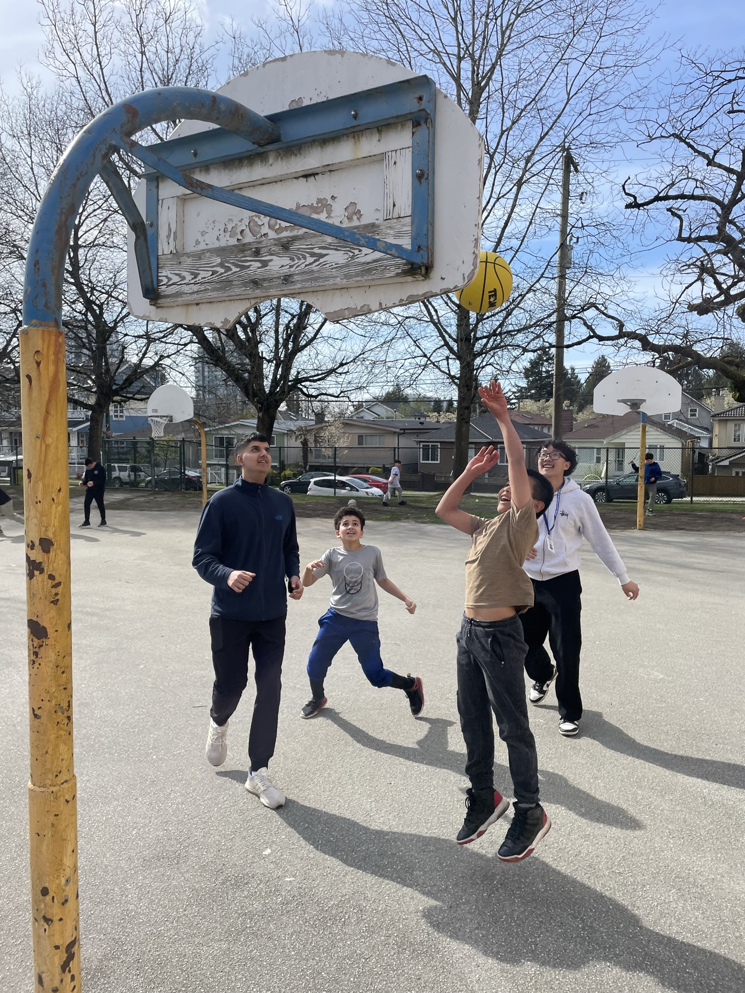 Four teenagers play basketball outside