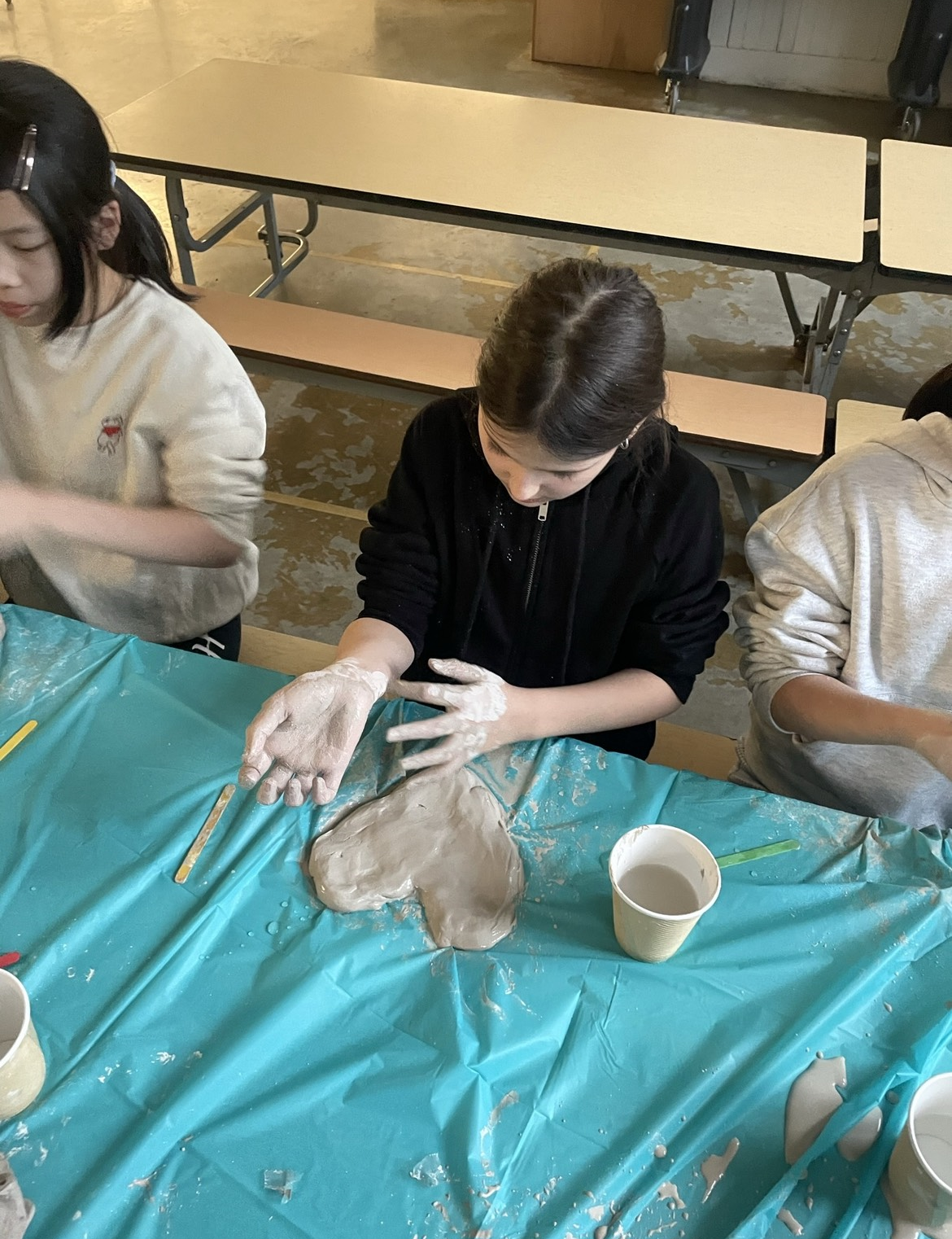 A teenager in a black sweater molds clay into the shape of a heart