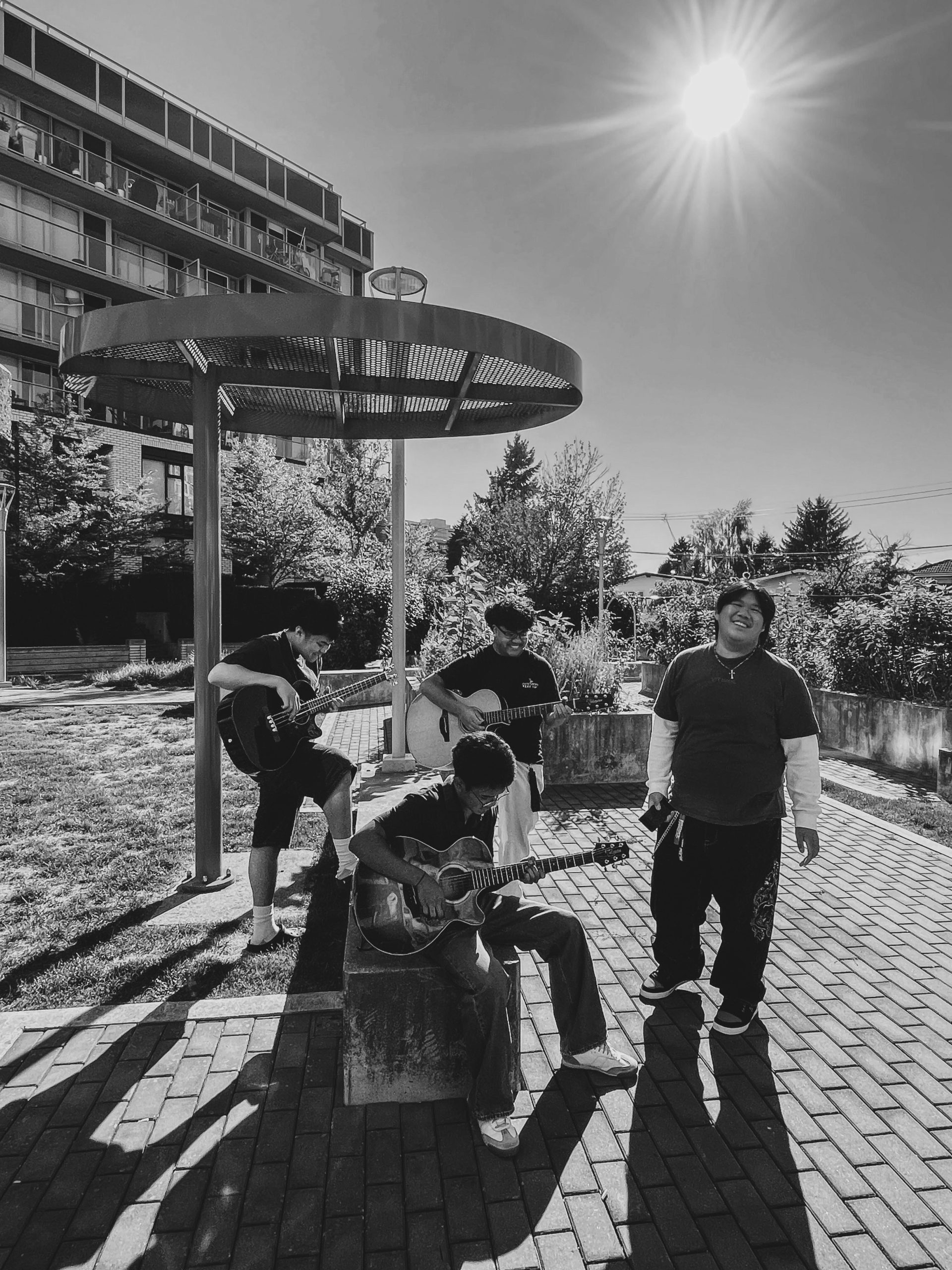 A black and white photo of four teenagers standing outside