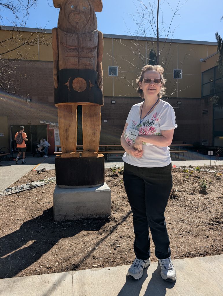 A woman stands in front of a wood carving in front of CNH